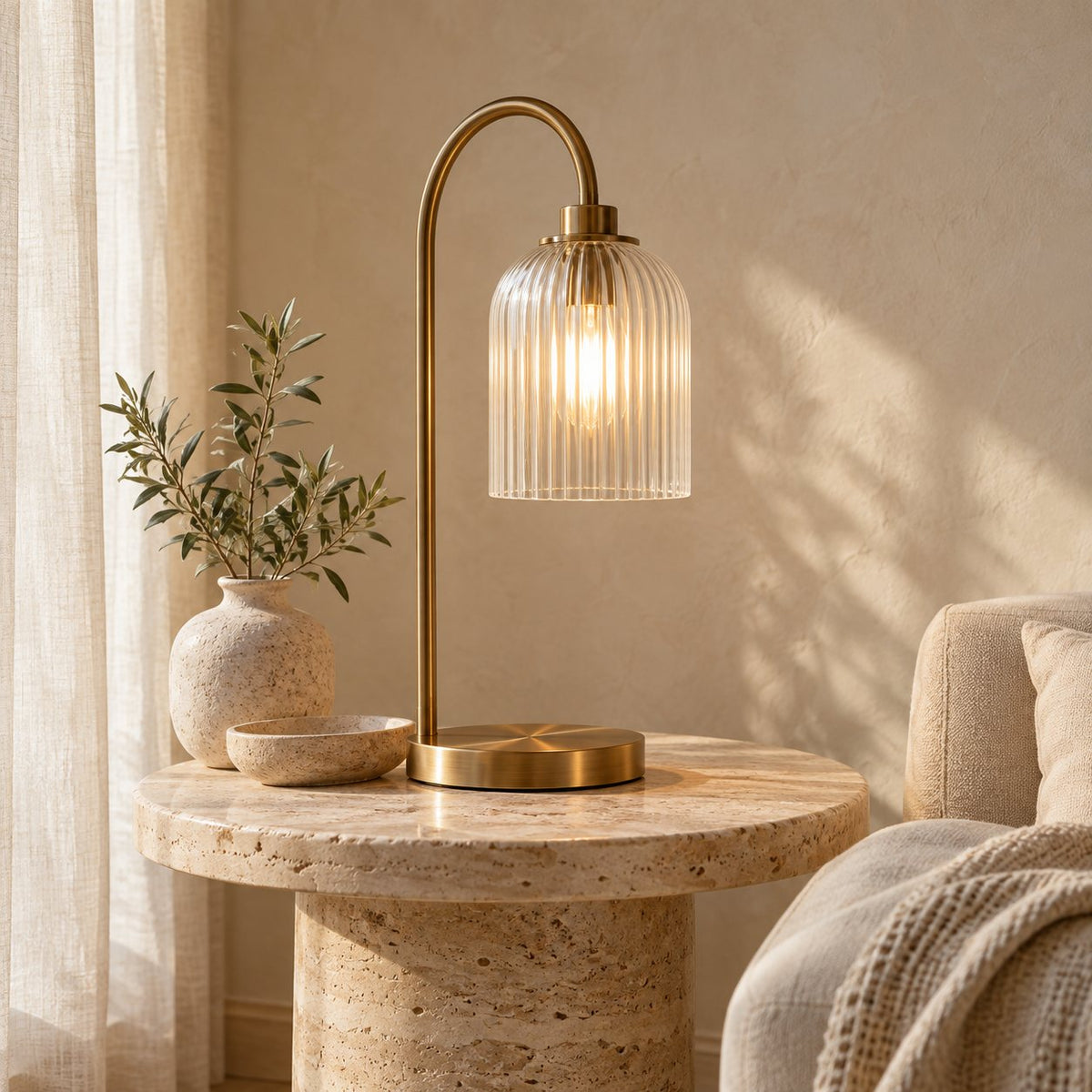 Lighting collection: a warm brass lamp with a fluted glass shade on a stone side table